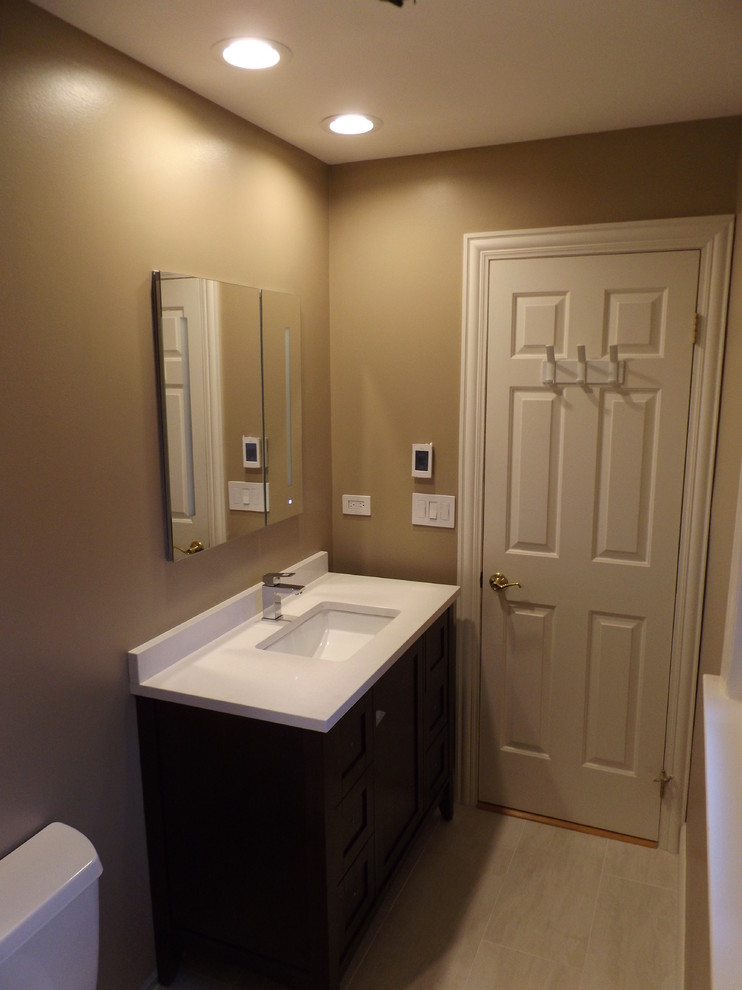 Idee per una stanza da bagno contemporanea di medie dimensioni con consolle stile comò, ante in legno scuro, WC monopezzo, piastrelle beige, pareti beige e lavabo integrato