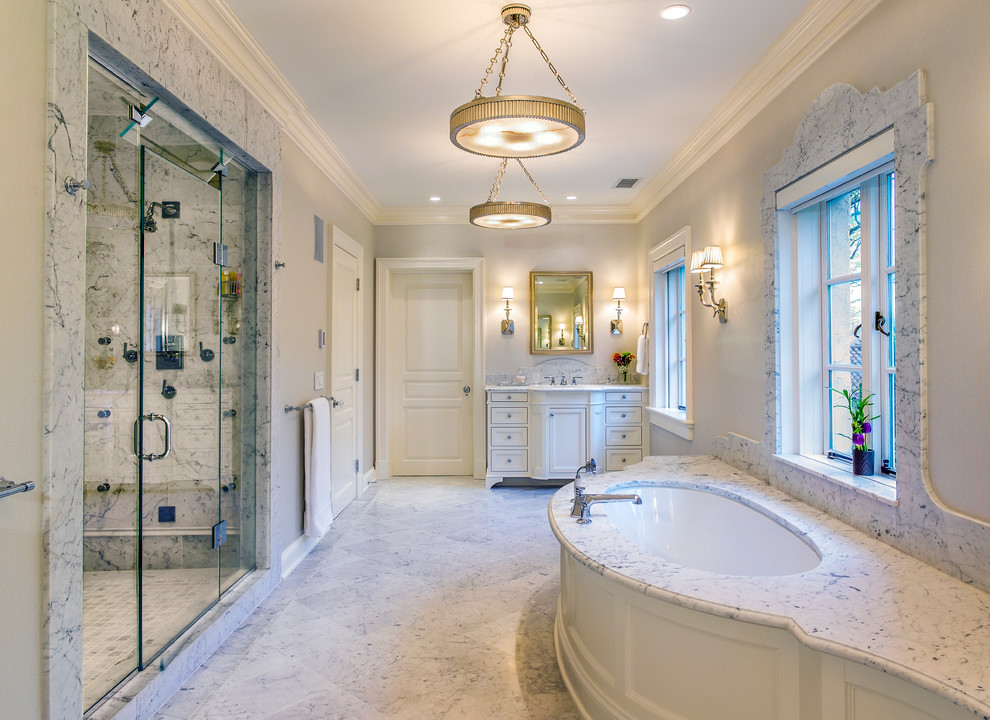 На фото: большая главная ванная комната в классическом стиле с врезной раковиной, фасадами с утопленной филенкой, белыми фасадами, мраморной столешницей, полновстраиваемой ванной, душем в нише, серой плиткой и серыми стенами