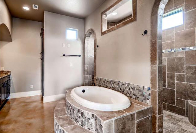Foto di una grande stanza da bagno padronale mediterranea con vasca da incasso, doccia aperta, piastrelle a mosaico, ante con bugna sagomata, ante in legno bruno, pareti grigie e pavimento in cemento