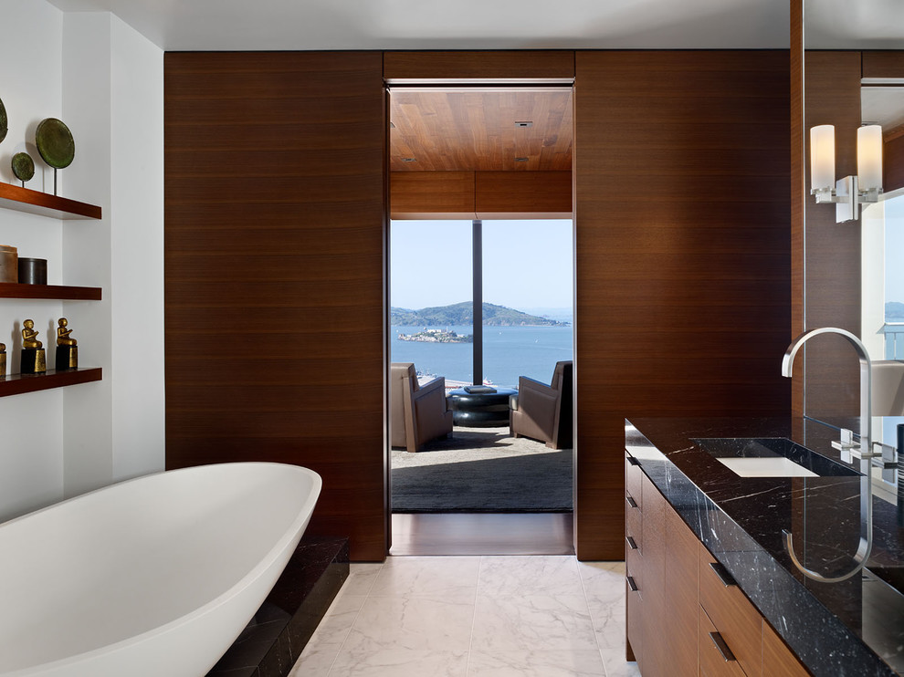 Modelo de cuarto de baño minimalista con armarios con paneles lisos, puertas de armario de madera oscura y bañera exenta