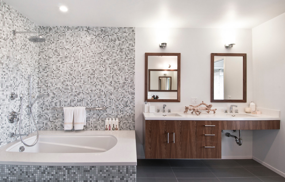Idee per una stanza da bagno minimal con lavabo sottopiano, ante lisce, ante in legno bruno, vasca/doccia, piastrelle grigie, piastrelle a mosaico e vasca sottopiano