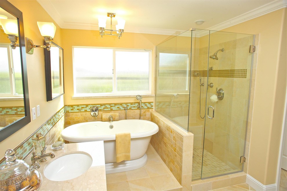 Свежая идея для дизайна: главная ванная комната среднего размера в классическом стиле с отдельно стоящей ванной, бежевой плиткой, желтыми стенами, полом из керамической плитки, монолитной раковиной, угловым душем, плиткой из травертина, столешницей из известняка, бежевым полом и душем с распашными дверями - отличное фото интерьера