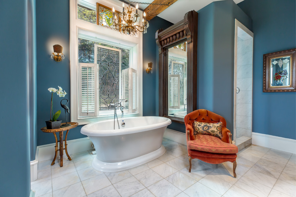 Cette image montre une salle de bain principale traditionnelle avec une baignoire indépendante, un carrelage blanc, un mur bleu et un sol blanc.