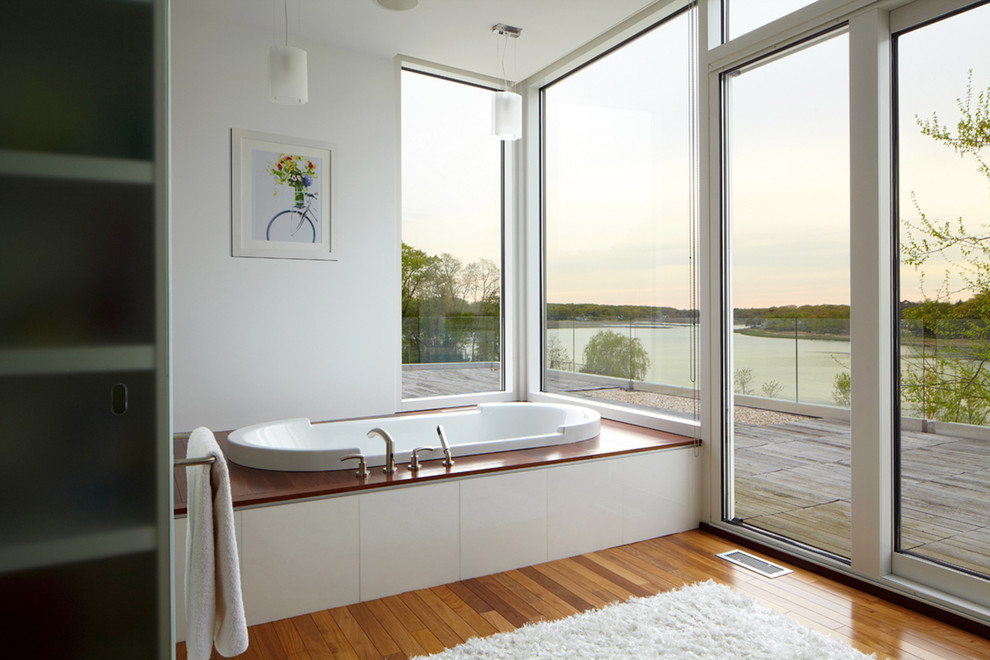 Alcove bathtub - mid-sized contemporary medium tone wood floor alcove bathtub idea in New York with white walls