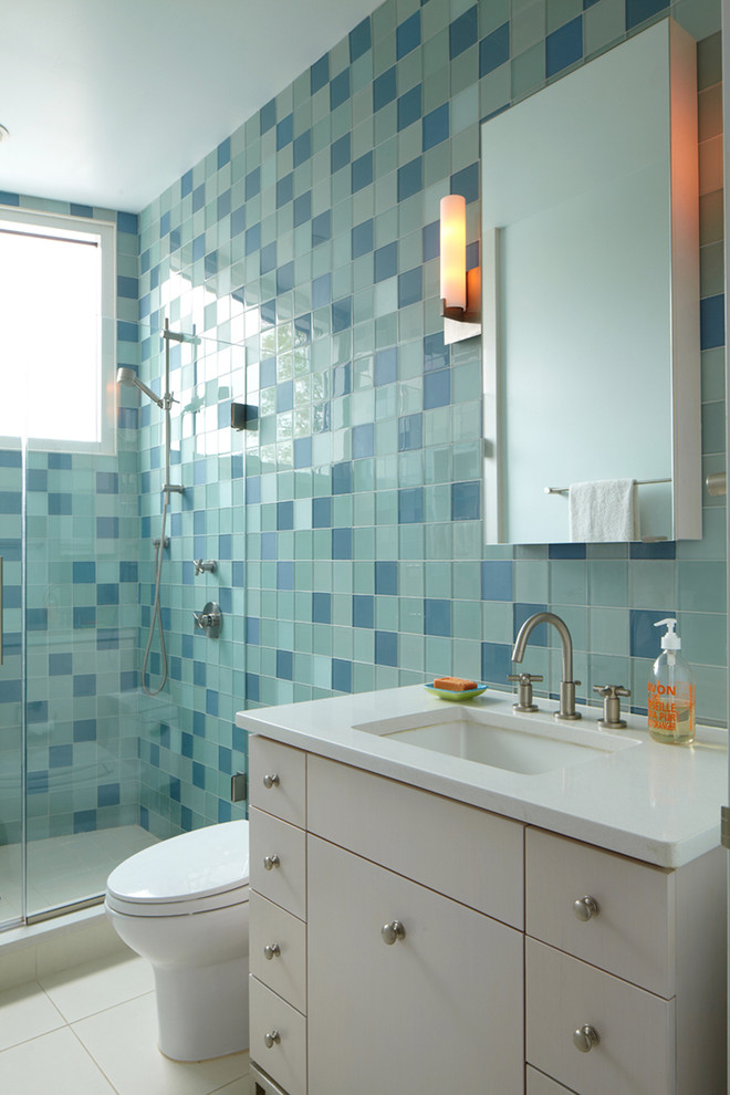Идея дизайна: ванная комната: освещение в стиле модернизм с врезной раковиной, плоскими фасадами, белыми фасадами, душем в нише, синей плиткой и стеклянной плиткой