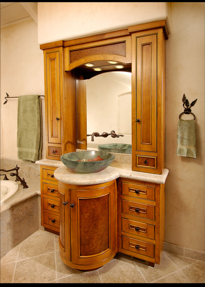 Aménagement d'une salle de bain méditerranéenne en bois brun avec une vasque, un placard avec porte à panneau encastré, une baignoire posée, un mur beige et un sol en ardoise.