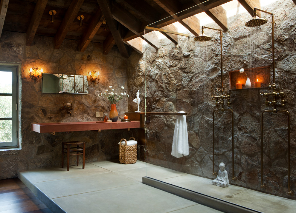 На фото: главная ванная комната в стиле рустика с душем без бортиков, серыми стенами, бетонным полом, раковиной с несколькими смесителями, столешницей из дерева, серым полом и открытым душем с