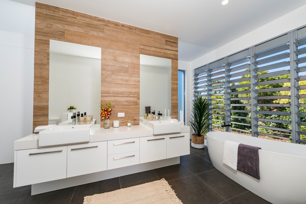 Exemple d'une salle de bain principale tendance avec un placard à porte plane, des portes de placard blanches, une baignoire indépendante, un mur marron, une vasque et un sol gris.