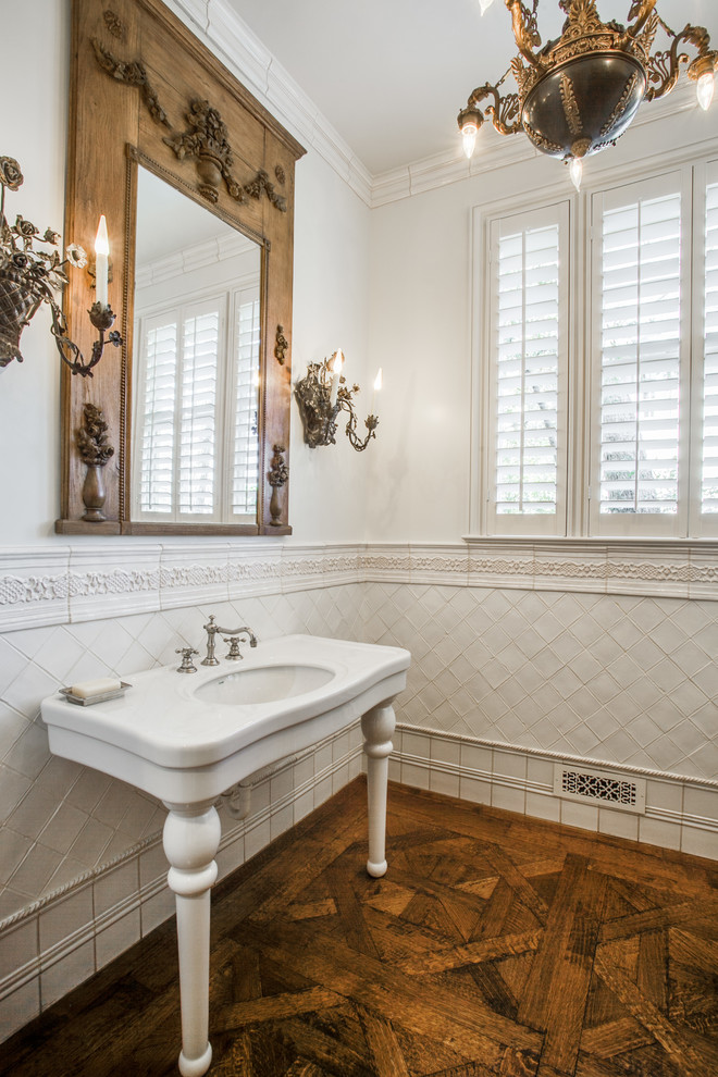 Modelo de cuarto de baño clásico con lavabo tipo consola, baldosas y/o azulejos blancos, paredes blancas y suelo de madera en tonos medios