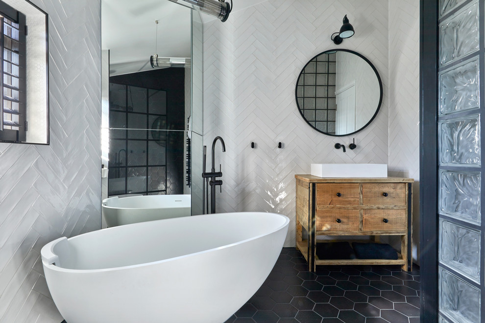 Inspiration for a medium sized contemporary ensuite bathroom in London with light wood cabinets, a freestanding bath, white tiles, ceramic tiles, white walls, a vessel sink, wooden worktops, black floors, brown worktops, a walk-in shower, a wall mounted toilet, porcelain flooring, an open shower and flat-panel cabinets.