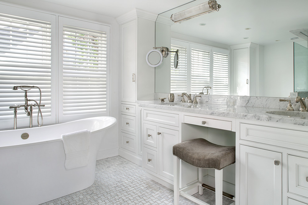 Cette photo montre une salle de bain principale chic de taille moyenne avec un placard à porte shaker, des portes de placard blanches, une baignoire indépendante et un sol gris.