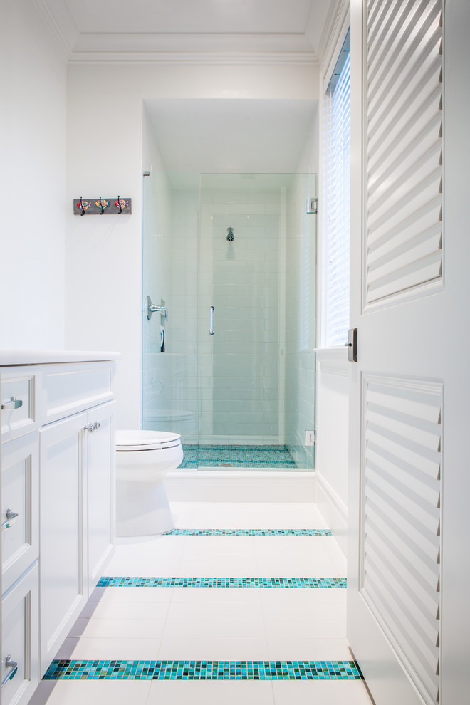 Example of a mid-sized beach style kids' blue tile and glass sheet ceramic tile alcove shower design in Miami with an undermount sink, recessed-panel cabinets, white cabinets, quartz countertops, a one-piece toilet and white walls