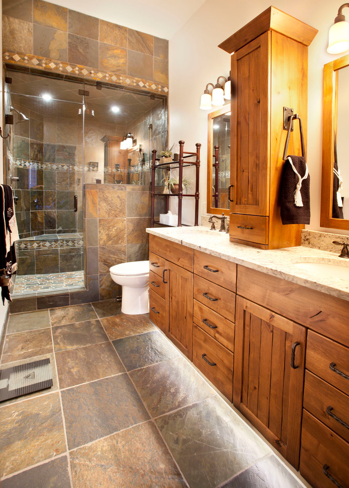 This is an example of a rustic bathroom in Vancouver with medium wood cabinets, a double shower, a one-piece toilet, multi-coloured tiles, stone tiles, beige walls, slate flooring, a submerged sink and granite worktops.