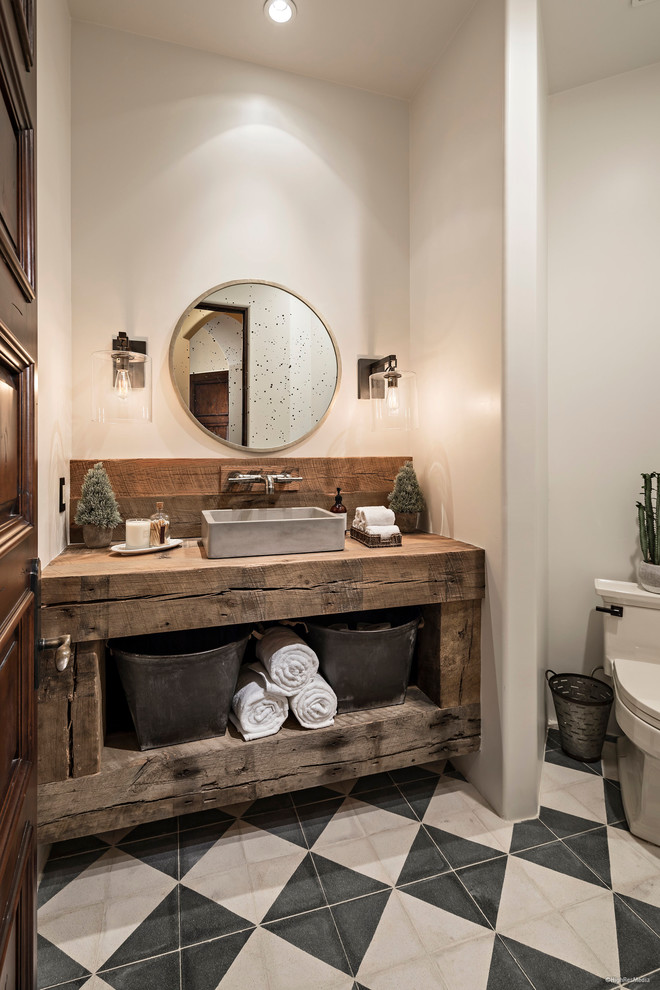 Foto på ett mellanstort rustikt badrum med dusch, med skåp i slitet trä, en toalettstol med separat cisternkåpa, svart och vit kakel, cementkakel, vita väggar, cementgolv, ett fristående handfat, träbänkskiva och öppna hyllor