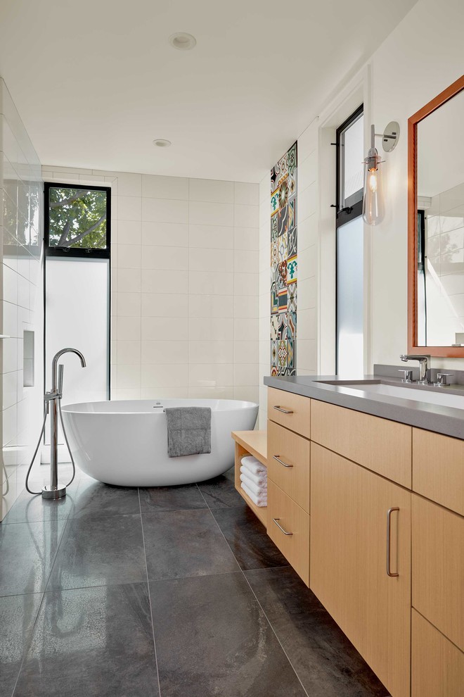 This is an example of a medium sized modern ensuite bathroom in San Francisco with flat-panel cabinets, light wood cabinets, a freestanding bath, multi-coloured tiles, white walls, ceramic flooring, grey floors, cement tiles, engineered stone worktops and a submerged sink.