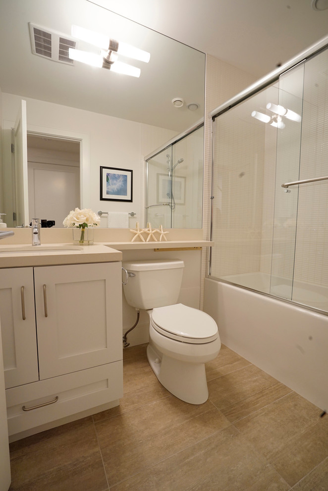 バンクーバーにある低価格の小さなトランジショナルスタイルのおしゃれな浴室 (コンソール型シンク、淡色木目調キャビネット、ラミネートカウンター、シャワー付き浴槽	、分離型トイレ、ベージュのタイル、石スラブタイル、ベージュの壁、磁器タイルの床) の写真