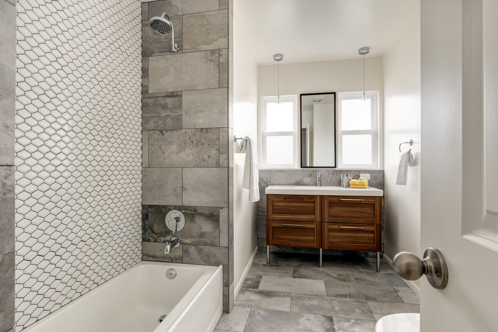 Bathroom - mid-sized contemporary gray tile and porcelain tile porcelain tile bathroom idea in San Diego with furniture-like cabinets, medium tone wood cabinets, a one-piece toilet, white walls, an integrated sink and solid surface countertops