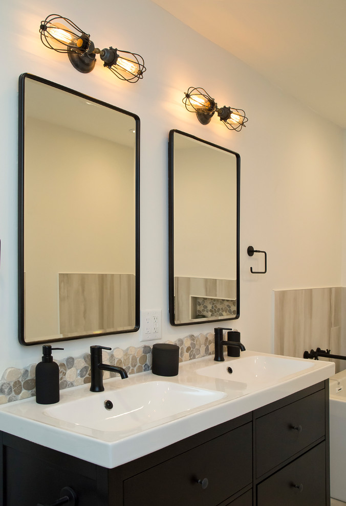 Inspiration for a mid-sized industrial master multicolored tile and porcelain tile porcelain tile and multicolored floor bathroom remodel in Raleigh with flat-panel cabinets, black cabinets, a two-piece toilet, white walls, an integrated sink, solid surface countertops and white countertops