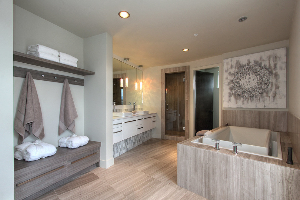 Bild på ett mycket stort funkis en-suite badrum, med släta luckor, vita skåp, ett hörnbadkar, ett fristående handfat, en dusch i en alkov, beige kakel, grå väggar, beiget golv och dusch med gångjärnsdörr