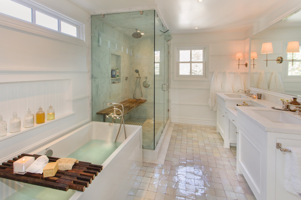 Bild på ett vintage badrum, med ett undermonterad handfat, luckor med infälld panel, vita skåp, ett fristående badkar, en hörndusch och vit kakel