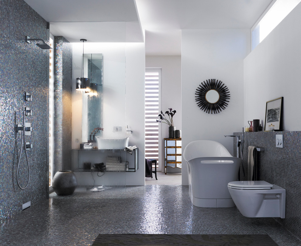 Inspiration för ett mellanstort funkis en-suite badrum, med ett fristående handfat, bänkskiva i glas, ett fristående badkar, en kantlös dusch, en vägghängd toalettstol, flerfärgad kakel, mosaik, vita väggar och mosaikgolv