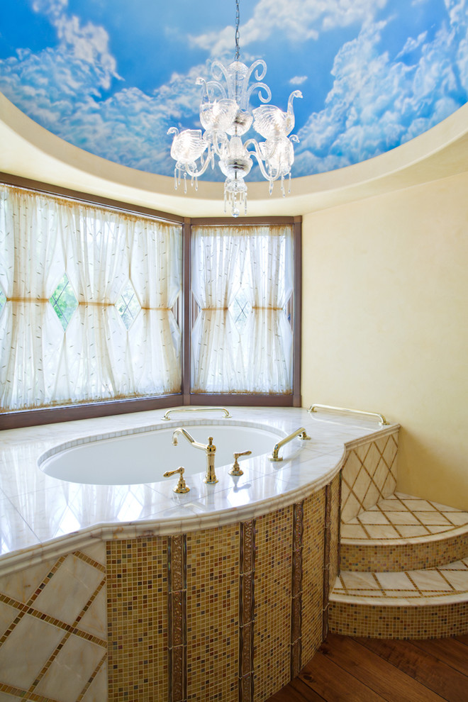 На фото: ванная комната в средиземноморском стиле с полновстраиваемой ванной, разноцветной плиткой, плиткой мозаикой, желтыми стенами, темным паркетным полом и окном