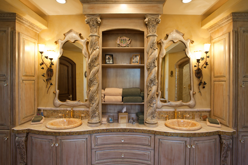 Bild på ett stort medelhavsstil badrum, med ett nedsänkt handfat, luckor med upphöjd panel, skåp i slitet trä, marmorbänkskiva, ett undermonterat badkar, en dusch i en alkov, en bidé, flerfärgad kakel, keramikplattor, gula väggar och mörkt trägolv