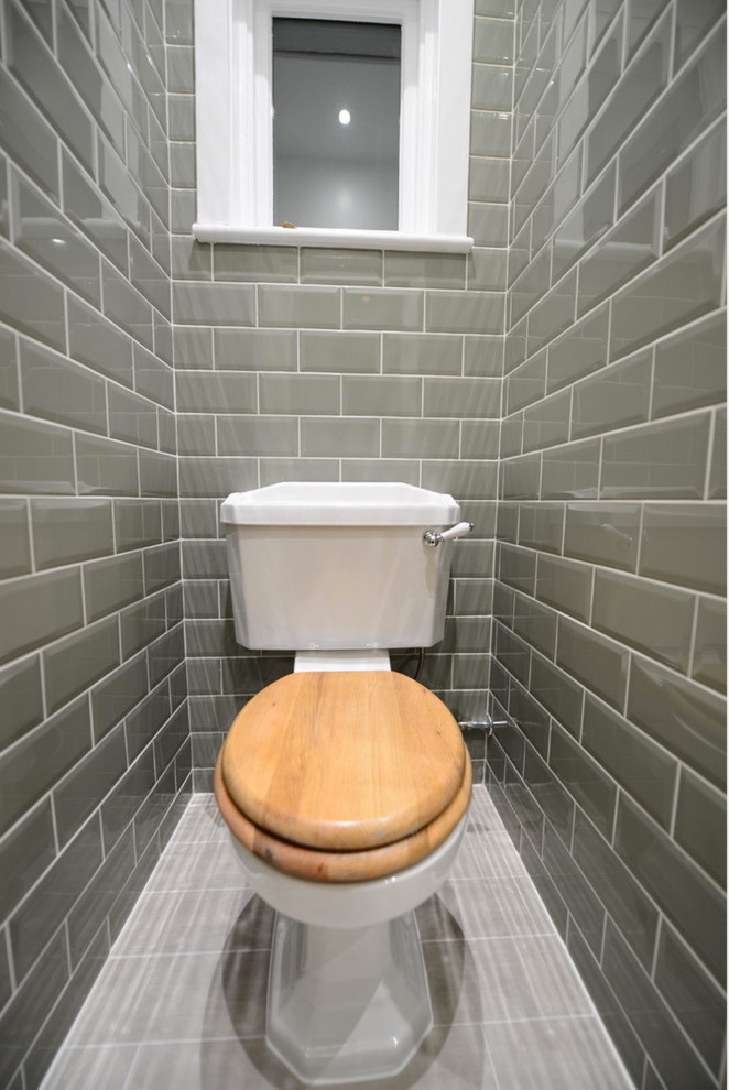 Small country cloakroom in Orange County with flat-panel cabinets, medium wood cabinets, a two-piece toilet, grey tiles, metro tiles, yellow walls, porcelain flooring and a vessel sink.