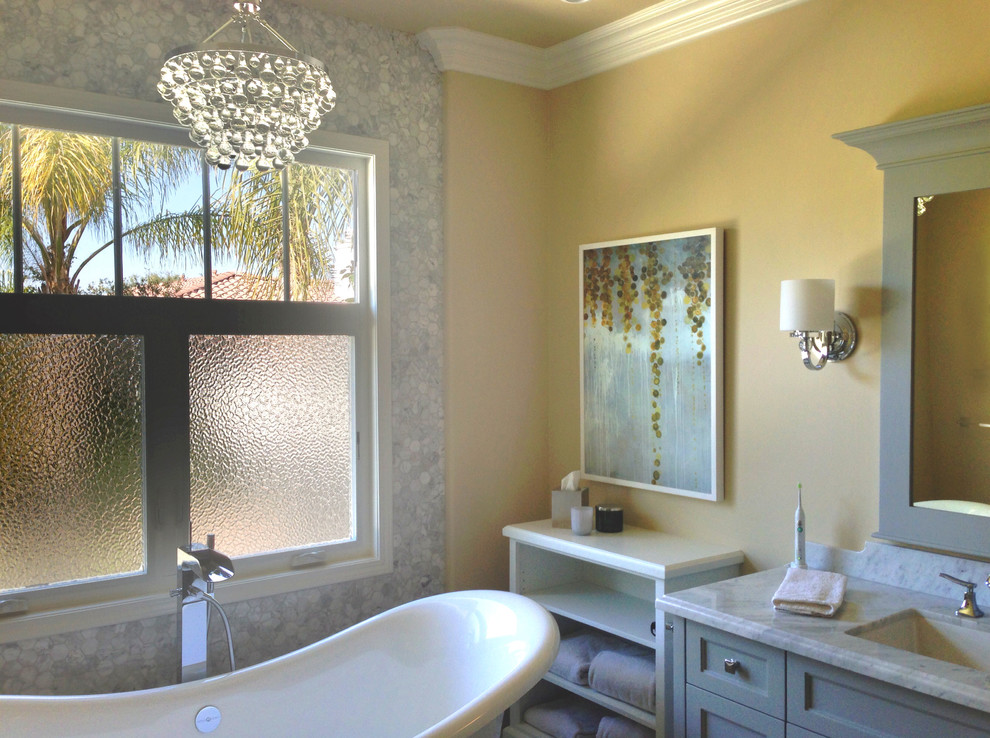 На фото: главная ванная комната среднего размера в классическом стиле с фасадами в стиле шейкер, серыми фасадами, отдельно стоящей ванной, унитазом-моноблоком, черно-белой плиткой, плиткой мозаикой, желтыми стенами, врезной раковиной и мраморной столешницей с