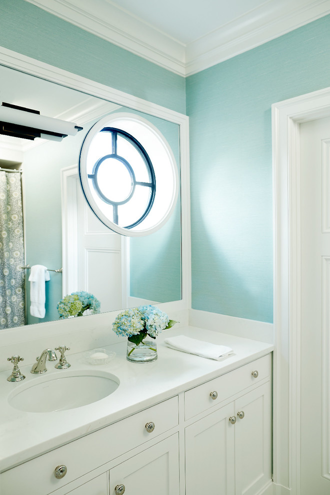 Inspiration pour une salle de bain traditionnelle avec un placard à porte shaker, des portes de placard blanches, un mur bleu, un lavabo encastré et un plan de toilette blanc.