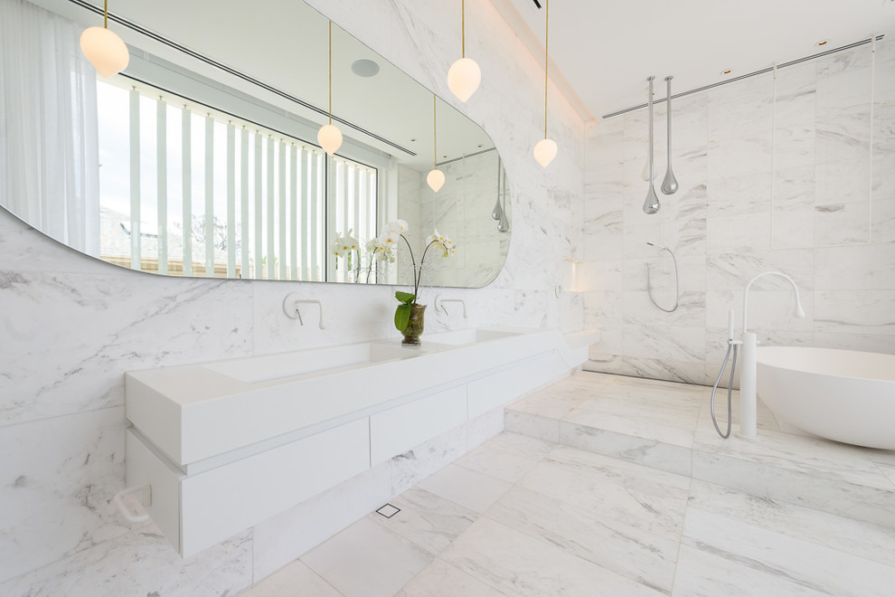 Modern inredning av ett en-suite badrum, med vita skåp, ett fristående badkar, en öppen dusch, stenkakel, vita väggar, marmorgolv, ett integrerad handfat och med dusch som är öppen