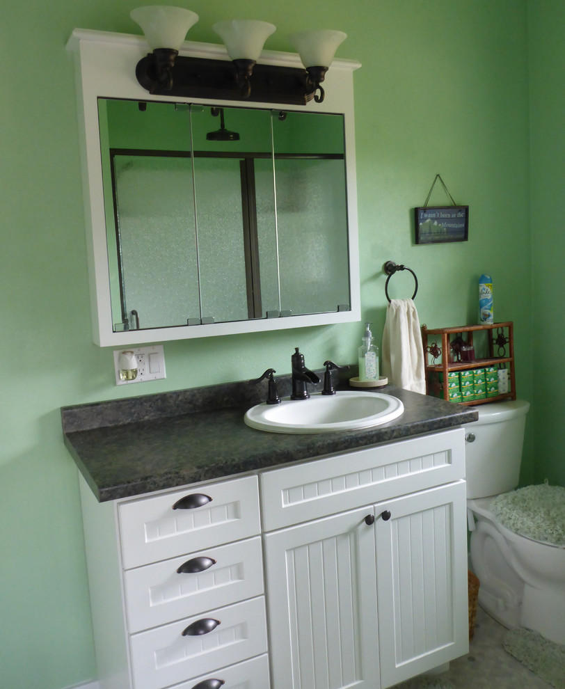 Cette image montre une salle de bain craftsman avec un placard à porte shaker, des portes de placard blanches, un sol en linoléum, un lavabo posé et un plan de toilette en stratifié.