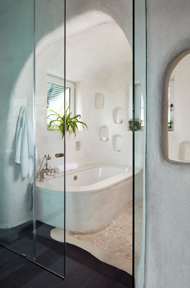 Cette image montre une salle de bain principale ethnique de taille moyenne avec une baignoire encastrée, un mur blanc et parquet foncé.