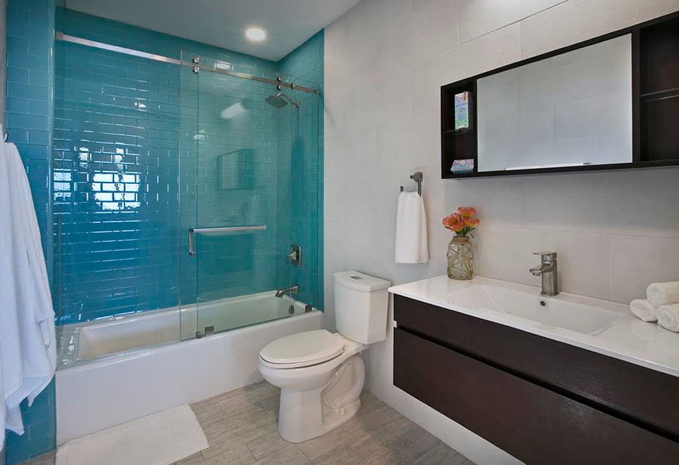 Idées déco pour une salle de bain contemporaine en bois foncé avec un placard à porte plane, une baignoire posée, un combiné douche/baignoire, WC séparés, un carrelage bleu, un carrelage en pâte de verre, un mur blanc, un sol en carrelage de porcelaine, un lavabo intégré et un plan de toilette en quartz modifié.