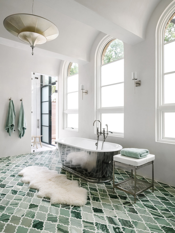 Cette image montre une salle de bain principale méditerranéenne avec une baignoire indépendante, un mur blanc et un sol vert.