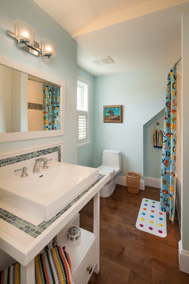 Idée de décoration pour une salle de bain marine de taille moyenne pour enfant avec des portes de placard blanches, WC à poser, mosaïque, un mur bleu et un sol en bois brun.