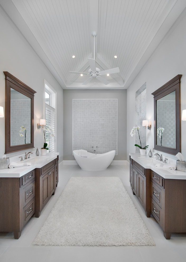 Идея дизайна: главная ванная комната в классическом стиле с фасадами с утопленной филенкой, темными деревянными фасадами, отдельно стоящей ванной, серой плиткой, серыми стенами, врезной раковиной и серым полом