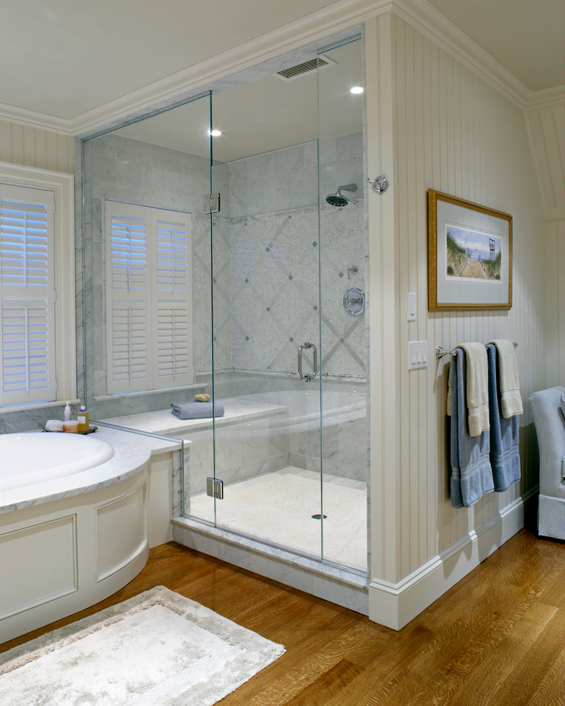 Immagine di una grande stanza da bagno padronale stile marinaro con top in marmo, vasca da incasso, pareti bianche e pavimento in legno massello medio