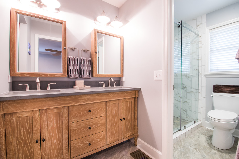 Alcove shower - mid-sized country 3/4 gray tile, white tile and stone tile porcelain tile alcove shower idea in Charleston with shaker cabinets, medium tone wood cabinets, a one-piece toilet, gray walls, an undermount sink and solid surface countertops