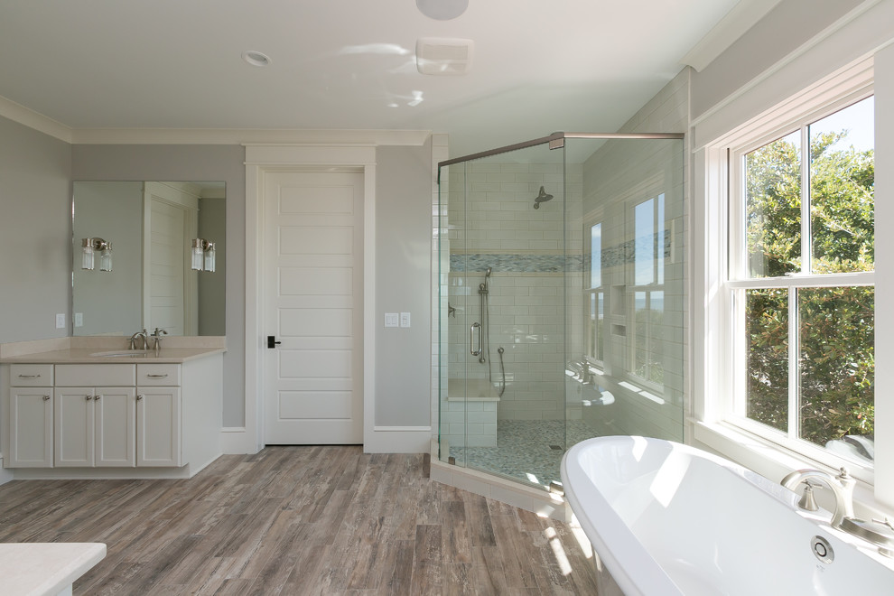 Example of a large beach style 3/4 beige tile and porcelain tile porcelain tile bathroom design in Charleston with shaker cabinets, white cabinets, a two-piece toilet, gray walls, an undermount sink and quartz countertops