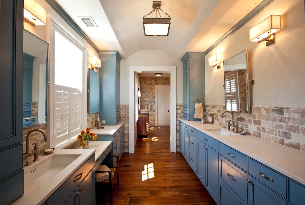Esempio di una stanza da bagno chic con lavabo sottopiano, ante con riquadro incassato, ante blu, piastrelle beige, piastrelle in pietra e top bianco
