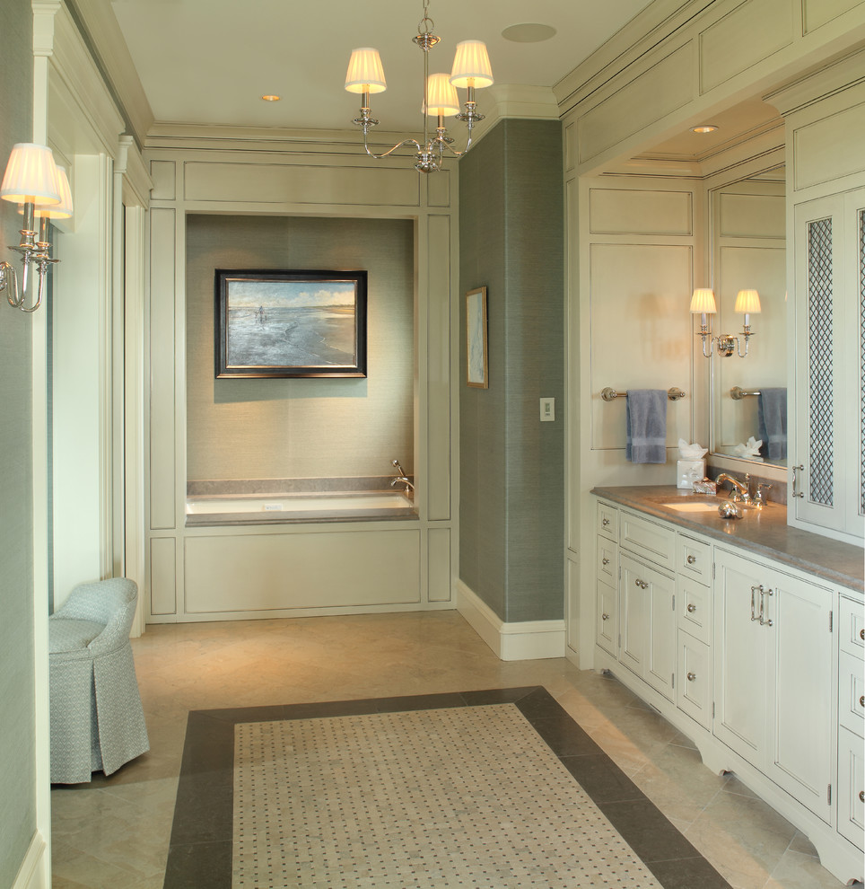 Foto på ett stort badrum, med vita skåp, ett undermonterat badkar, ett undermonterad handfat och beiget golv