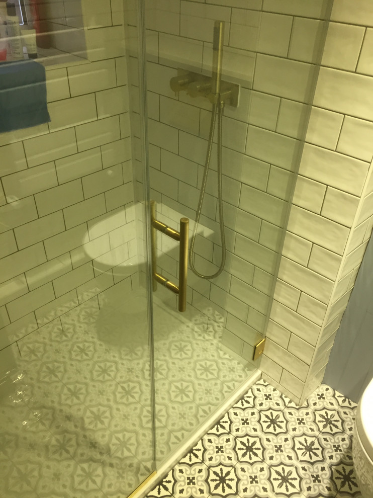 Design ideas for a small contemporary shower room bathroom in London with beaded cabinets, blue cabinets, a built-in shower, a wall mounted toilet, white tiles, ceramic tiles, white walls, cement flooring, a console sink, marble worktops, multi-coloured floors, a hinged door and white worktops.