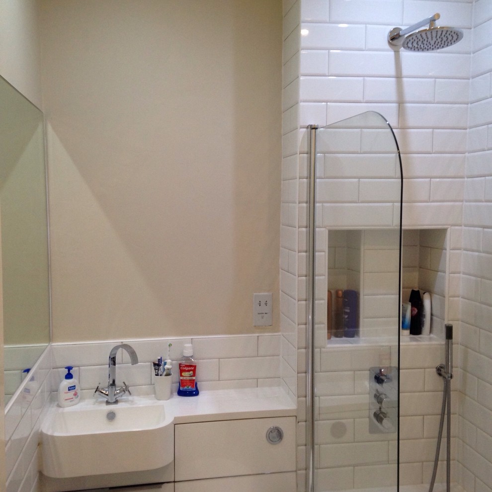 Exempel på ett mellanstort modernt badrum för barn, med ett nedsänkt handfat, släta luckor, vita skåp, bänkskiva i akrylsten, ett platsbyggt badkar, en kantlös dusch, en toalettstol med hel cisternkåpa, vit kakel, porslinskakel, vita väggar och klinkergolv i porslin