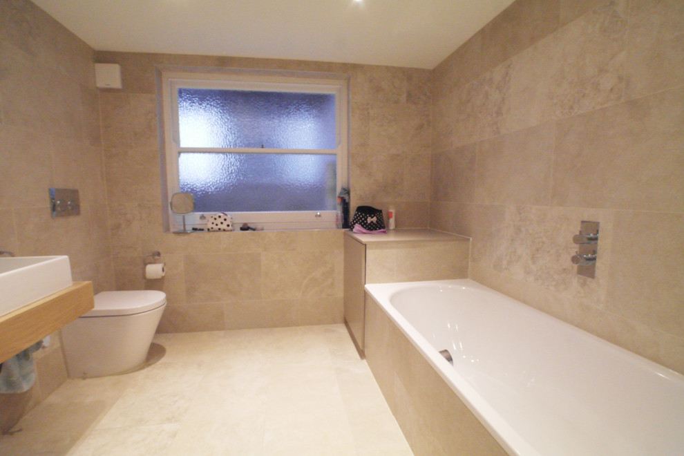 Immagine di una stanza da bagno padronale design di medie dimensioni con ante lisce, ante grigie, vasca da incasso, doccia aperta, piastrelle beige, piastrelle in gres porcellanato, lavabo sospeso e top piastrellato
