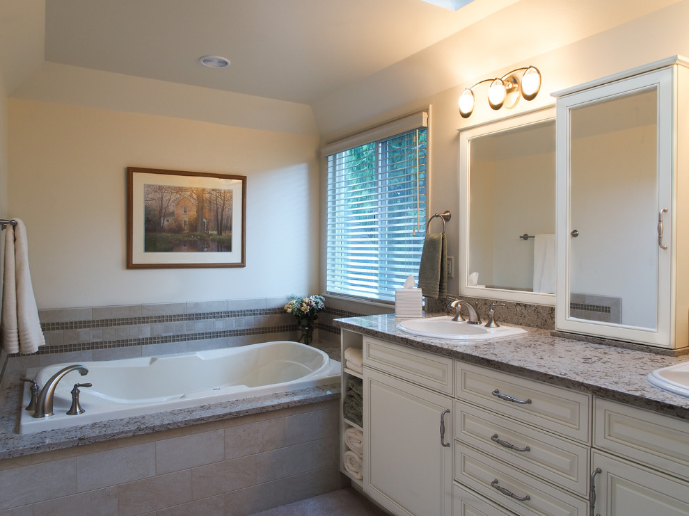 Example of a large classic master beige tile and porcelain tile porcelain tile, beige floor, double-sink and tray ceiling bathroom design in Seattle with a drop-in sink, raised-panel cabinets, white cabinets, quartz countertops, a two-piece toilet, white walls, multicolored countertops and a built-in vanity