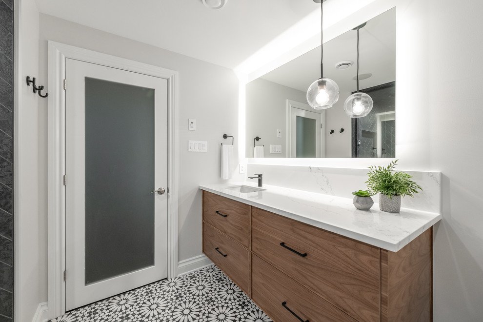 Example of a mid-sized transitional 3/4 black tile and porcelain tile porcelain tile and multicolored floor alcove shower design in Ottawa with an undermount sink, a hinged shower door, flat-panel cabinets, medium tone wood cabinets, a two-piece toilet, gray walls, quartz countertops and white countertops