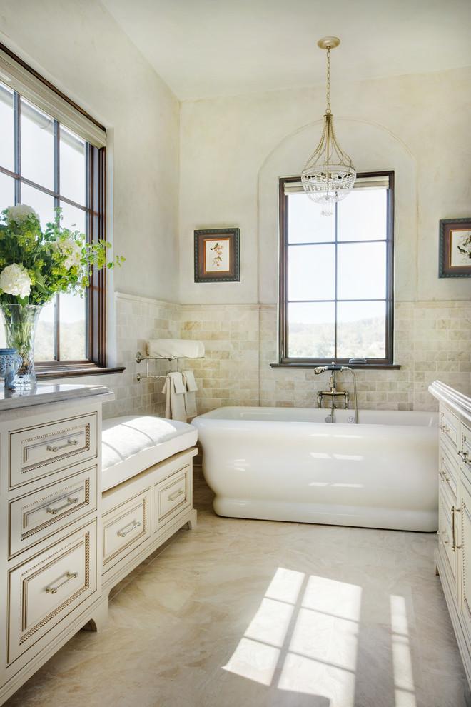 Inspiration för ett medelhavsstil en-suite badrum, med luckor med profilerade fronter, beige skåp, ett fristående badkar, beige kakel, marmorkakel, beige väggar, marmorgolv, marmorbänkskiva, beiget golv och ett undermonterad handfat
