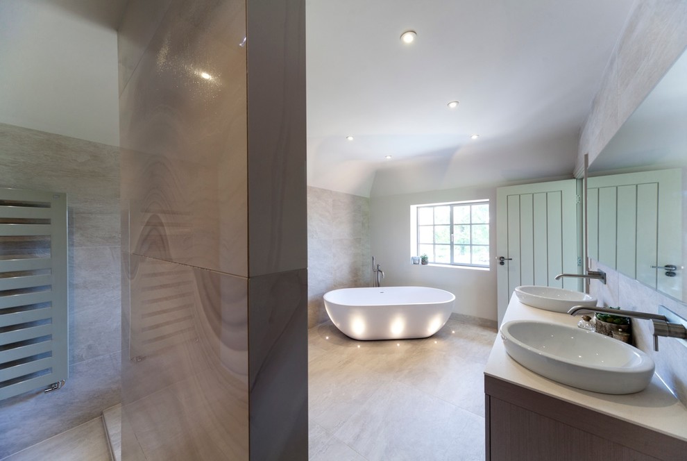 Design ideas for a large contemporary ensuite bathroom in Cheshire with a built-in sink, freestanding cabinets, light wood cabinets, granite worktops, a freestanding bath, a walk-in shower, a wall mounted toilet, beige tiles, porcelain tiles, beige walls and porcelain flooring.