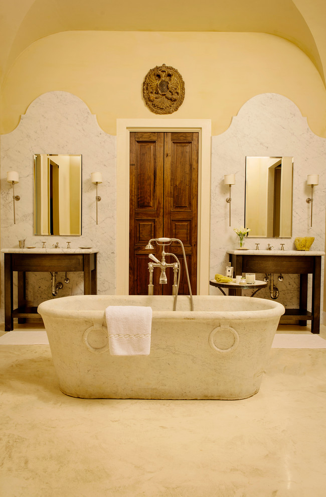 Medelhavsstil inredning av ett mycket stort en-suite badrum, med öppna hyllor, skåp i mörkt trä, ett fristående badkar, grå kakel, stenkakel, gula väggar, marmorgolv, marmorbänkskiva och ett undermonterad handfat